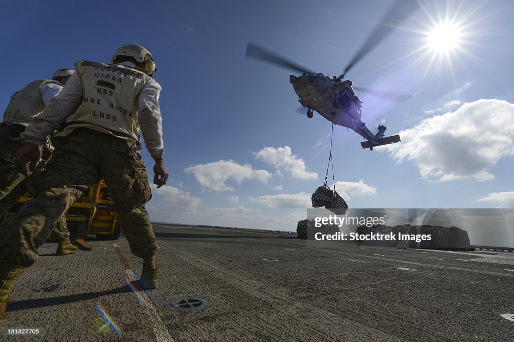 An MH-60S Sea Hawk helicopter lowers pallets of supplies onto USS Bonhomme Richard.