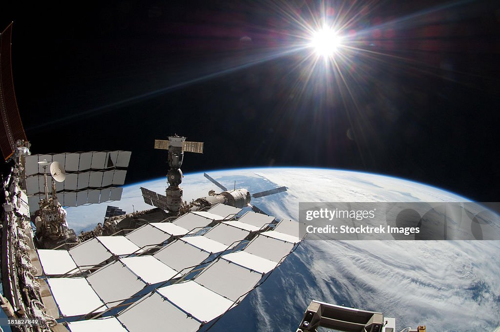 The bright sun, a portion of the International Space Station and Earth's horizon. The image was taken using a fish-eye lens attached to an electronic still camera.  