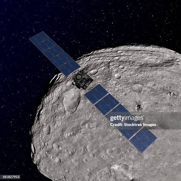 artist's concept showing nasa's dawn spacecraft orbiting the giant asteroid vesta. - exploratory spacecraft stock-grafiken, -clipart, -cartoons und -symbole