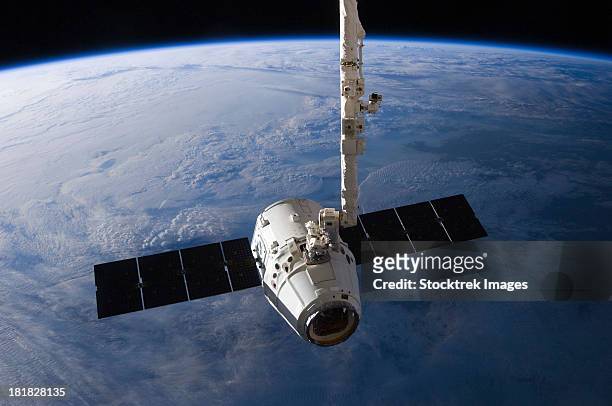 the spacex dragon cargo craft prior to being released from the canadarm2. - satellite orbiting stock pictures, royalty-free photos & images
