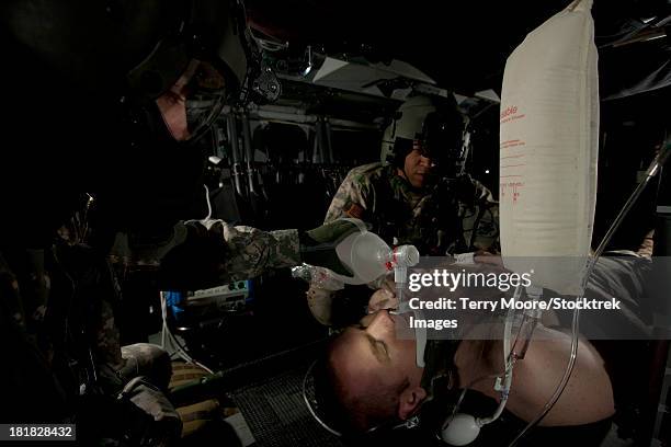 u.s. army medevac crew chief assists the flight medic by simulating ventilation of a mock patient during trainingâ aboard a uh-60l black hawk helicopter. - ac moore stock-fotos und bilder