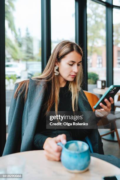businesswoman using smartphone on coffee break in brightly lit cafe - coffee shop chat stock-fotos und bilder