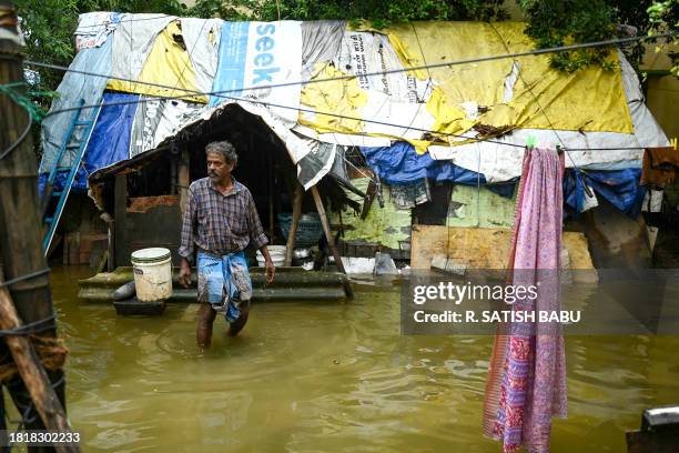 Man walks near his house in a flooded street after heavy rains ahead of Cyclone Michaung's landfall in Chennai on December 3, 2023.