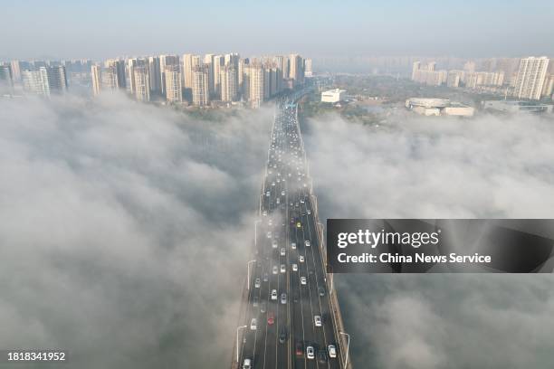 Aerial view of a bridge and buildings enveloped in thick fog on November 28, 2023 in Changsha, Hunan Province of China.