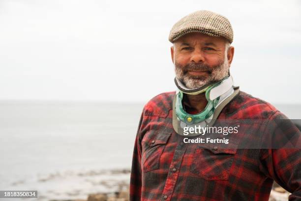 a mature man wearing an orthopedic neck brace after cervical stenosis surgery. - cervical collar stock pictures, royalty-free photos & images