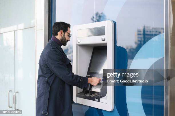 arab businessman using an atm - banking district stock pictures, royalty-free photos & images