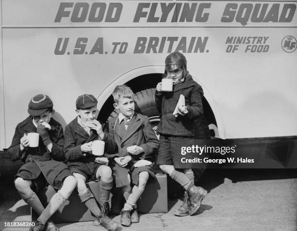 School boys drinking tea and eating sandwiches in front of a Food Flying Squad mobile canteen, part of the Queen's Messenger Food Convoy which is...