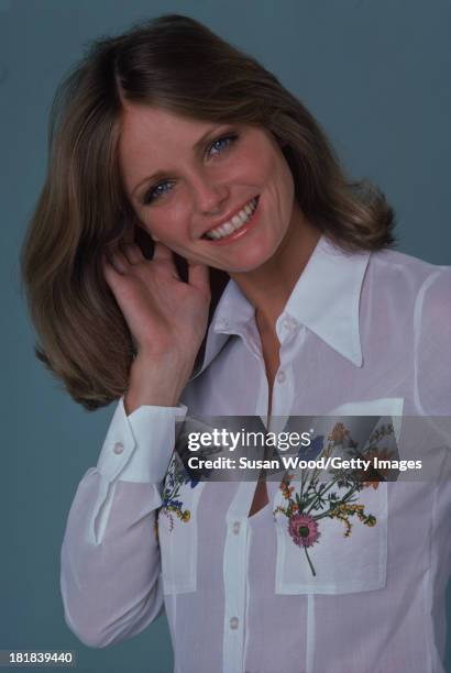 Portrait of American model and actress Cheryl Tiegs as she poses, dressed in a white shirt, with floral embroidery on the pockets, 1974. The photo...