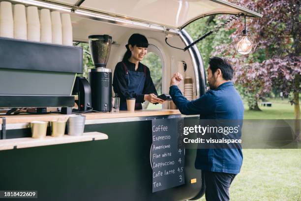 japanese businessman paying at mobile coffee trailer - food truck payments stock pictures, royalty-free photos & images