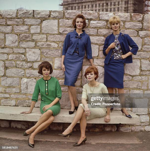 Four female fashion models posed wearing skirt suits and outfits for the winter season in various styles, from left, a green dress with button...