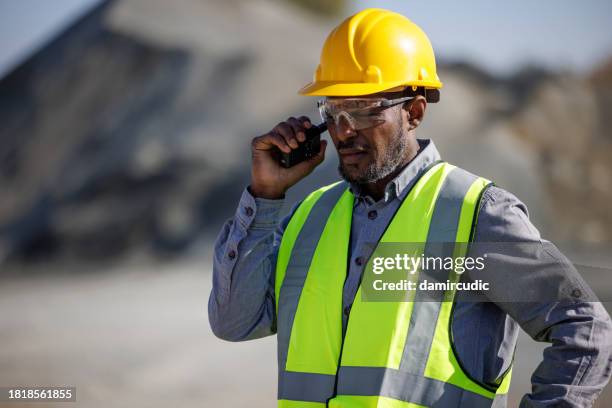 portrait d’un ouvrier ou d’un ingénieur de l’industrie portant un casque de sécurité et des lunettes de protection à l’aide d’un talkie-walkie sur un chantier de construction - mineur de charbon photos et images de collection
