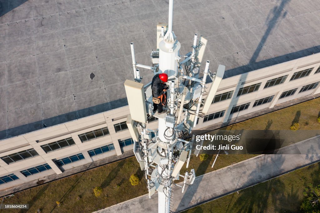 Engineer uses smartphone while repairing cell tower
