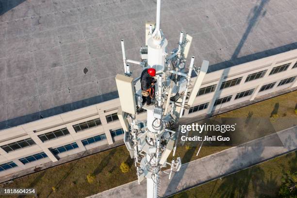 engineer uses smartphone while repairing cell tower - telecoms engineer stock pictures, royalty-free photos & images