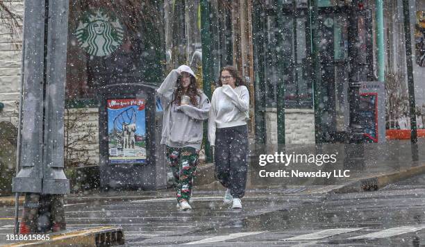 Pedestrians walk along Main Street, in Port Jefferson, New York, as a mixture of snow and rain fell from the Nor'easter that passed over Long Island...