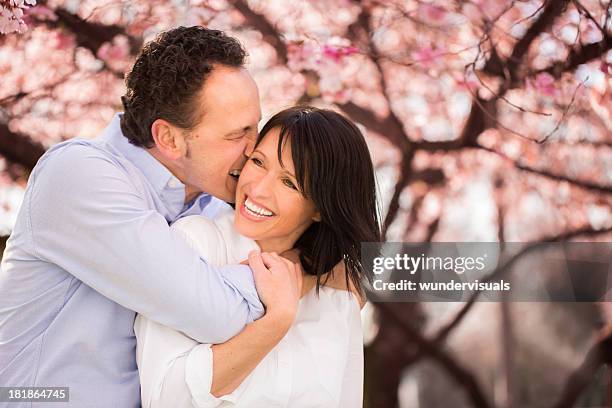 mature man playfully biting his wife's earlobe - earlobe stockfoto's en -beelden