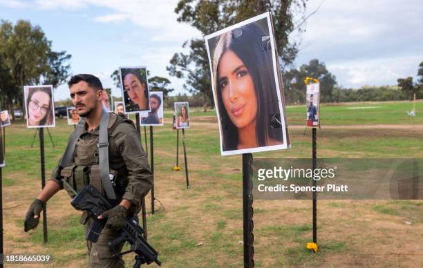 Soldier walks among pictures of victims of the Noval music festival at the site of the October 7th massacre near Kibbutz Re'im and the border with...