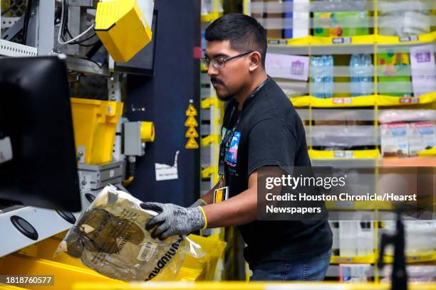 Jiovanni Martinez places an item in a crate to be sent on to be boxed for shipping at the Amazon HOU6 Fulfillment Center on Monday, Nov. 27, 2023 in...