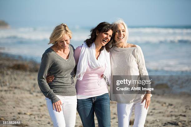 trio of women walking at the beach - mature women friends stock pictures, royalty-free photos & images