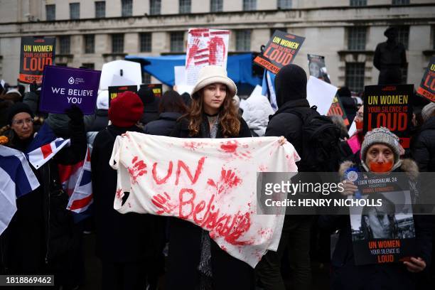 Demonstrators hold posters reading "UN Women, your silence is loud" along with a red paint-stained sheet reading "UNbelievable" during a rally in...