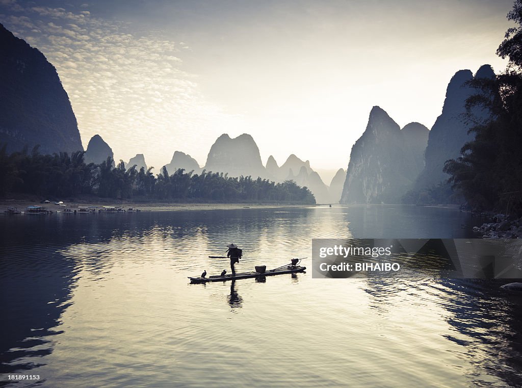 Fishermen on li river surrounded by mountains