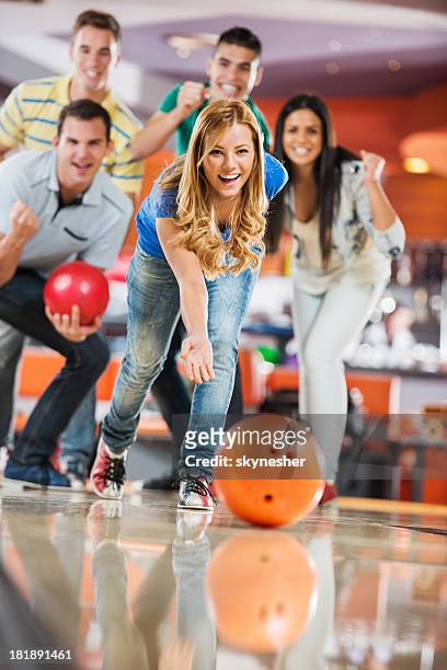 friends cheering while girl is throwing a bowling ball - bowling alley stock pictures, royalty-free photos & images