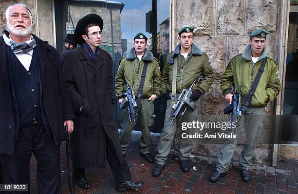 Israeli soldiers stand guard as ultra-Orthodox Jewish men watch the funeral procession for Rabbi Yaakov Fisher February 27, 2003 in Jerusalem,...