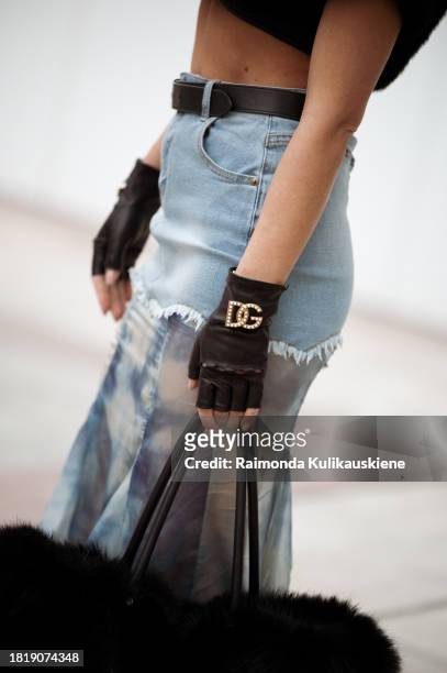 Guest wears long skirt part blue denim, part white and blue silk with a black belt, black leather gloves from Dolce and Gabbana, black big fur bag...