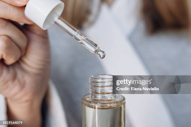 serum mineral oil facial care. skin care beauty products, bottle with pipette with serum or cream or lotion for care in the hands of woman - retinol stock pictures, royalty-free photos & images