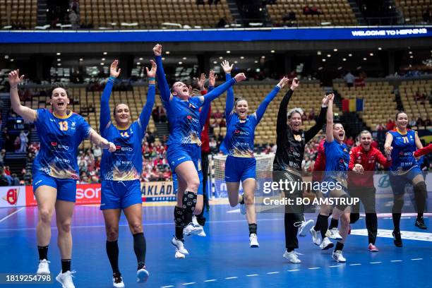 Romania's players celebrate after the preliminary round Group E match between Romania and Serbia of the IHF World Women's Handball Championship in...