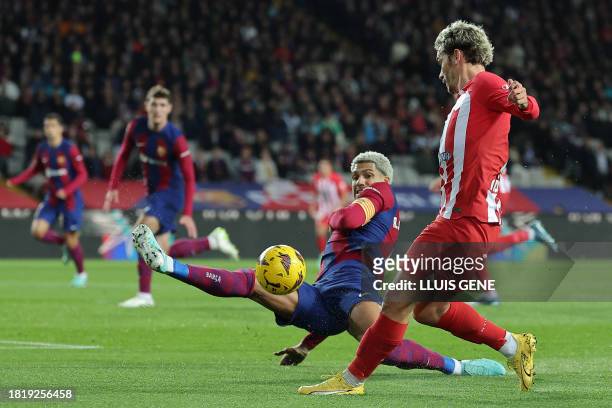 Atletico Madrid's French forward Antoine Griezmann is tackled by Barcelona's Uruguayan defender Ronald Araujo during the Spanish league football...