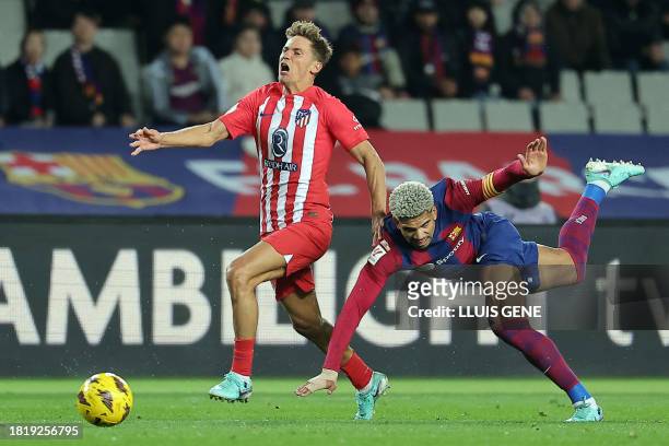 Barcelona's Uruguayan defender Ronald Araujo falls down as he challenges Atletico Madrid's Spanish midfielder Marcos Llorente during the Spanish...