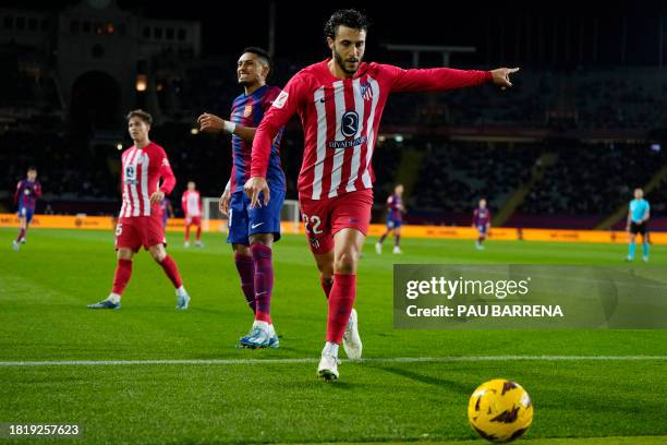 Barcelona's Brazilian forward Raphinha reacts as Atletico Madrid's Spanish defender Mario Hermoso signals after the ball cossed the touchline during...