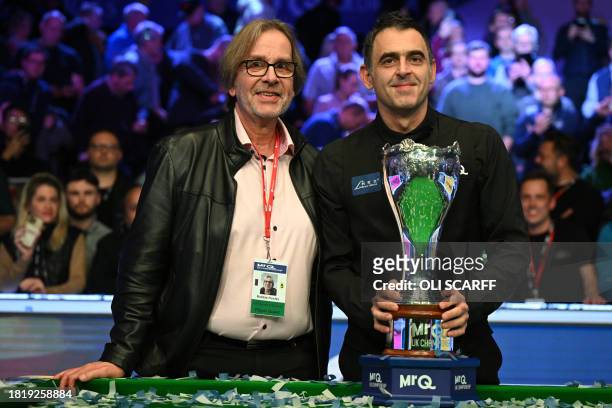 England's Ronnie O'Sullivan poses with the trophy and his friend Robbie Huxley after his victory over China's Ding Junhui in the final of the 2023...