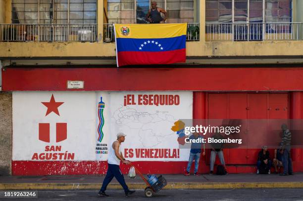 Pedestrians near a mural that reads "The Essequibo is Venezuela," during a referendum vote in Caracas, Venezuela, on Sunday, Dec. 3, 2023. Following...