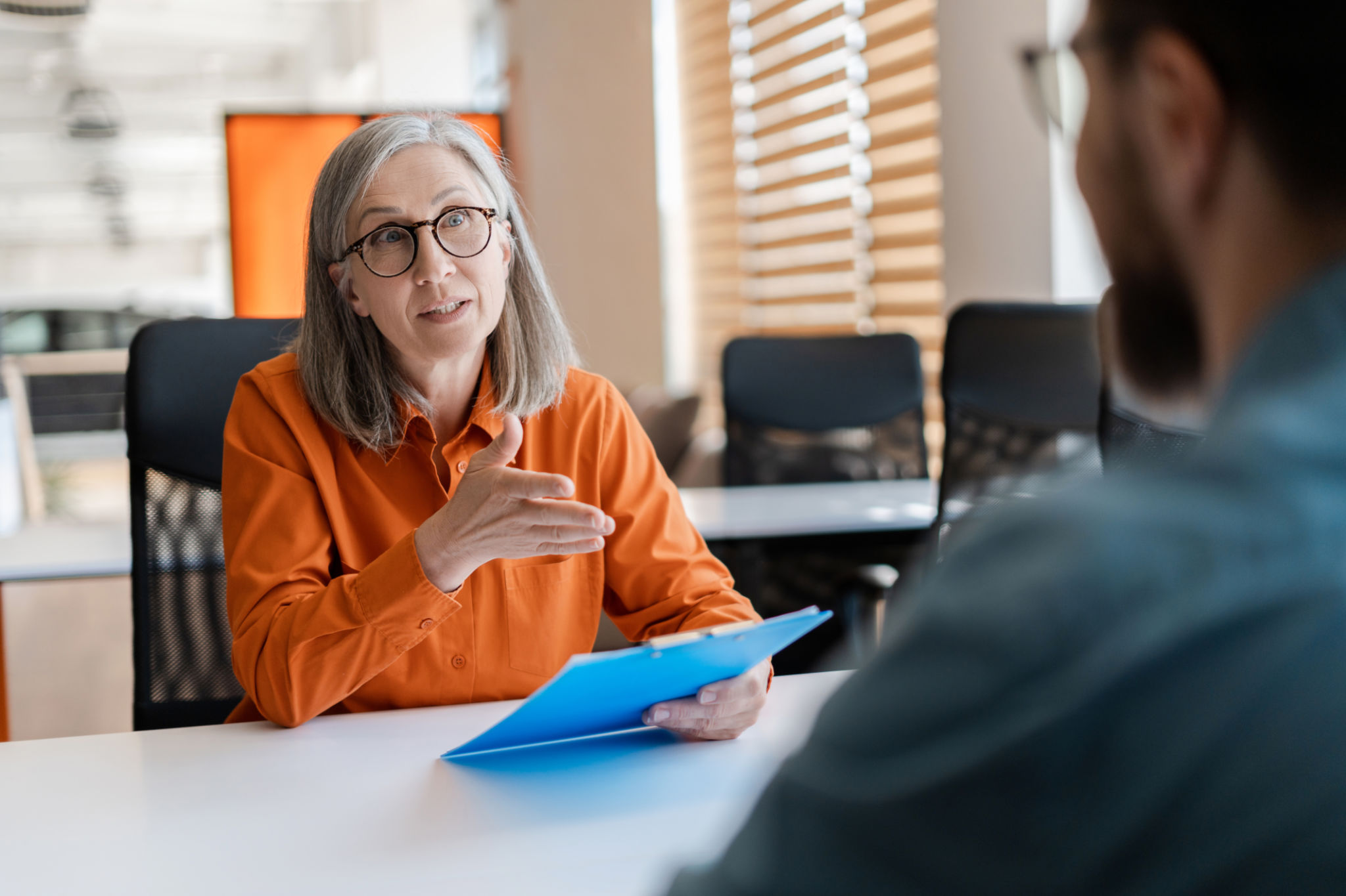 Business woman, employer holding resume listening young candidate at job interview. Group of business people talking, meeting, sharing ideas in modern office. Human resources concept Business woman, employer holding resume listening young candidate at job interview. Group of business people talking, meeting, sharing ideas in modern office. Human resources concept