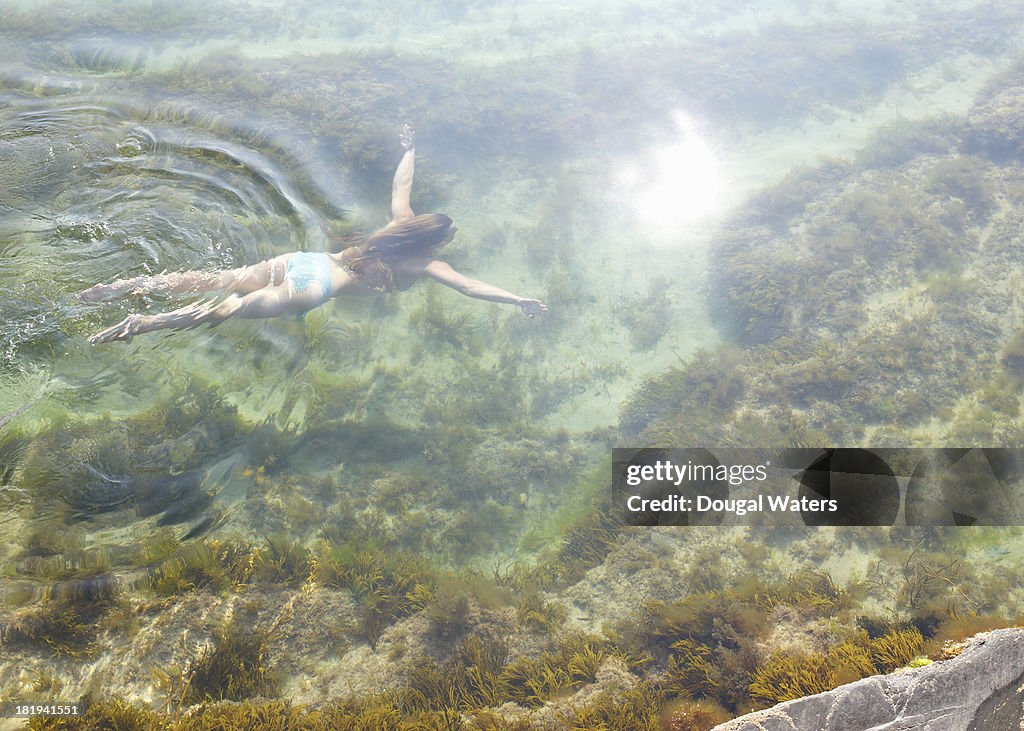 Woman swimming in idyllic rock pool.