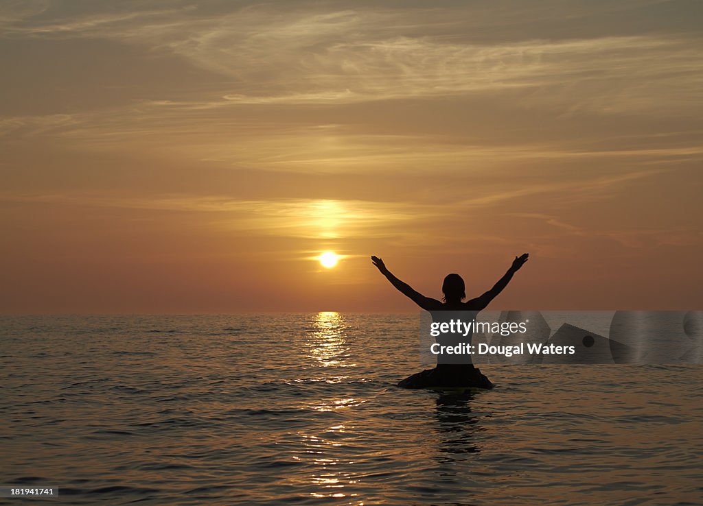 Silhouette of surfer at sunset.