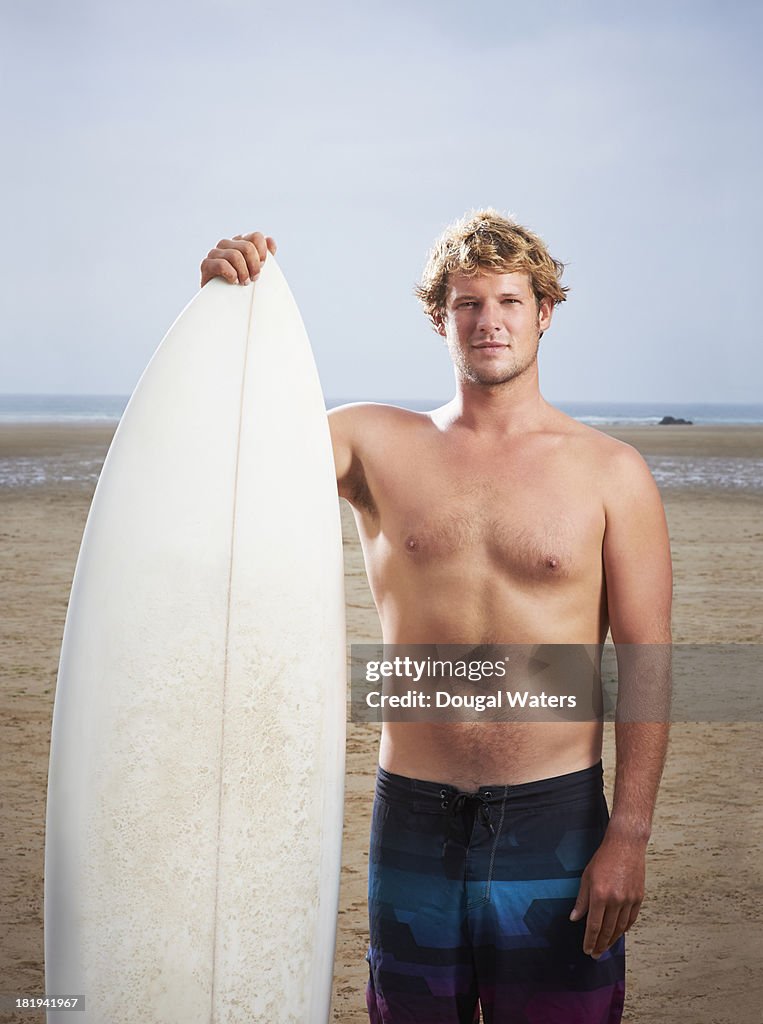 Portrait of surfer with surfboard at beach.