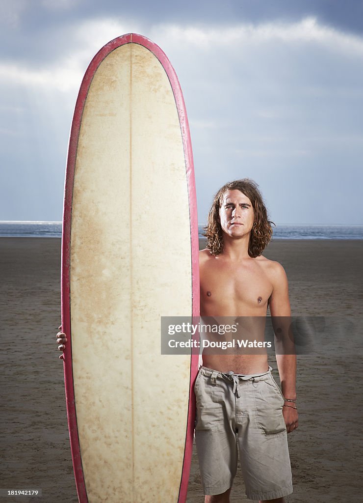 Portrait of surfer with board at beach.