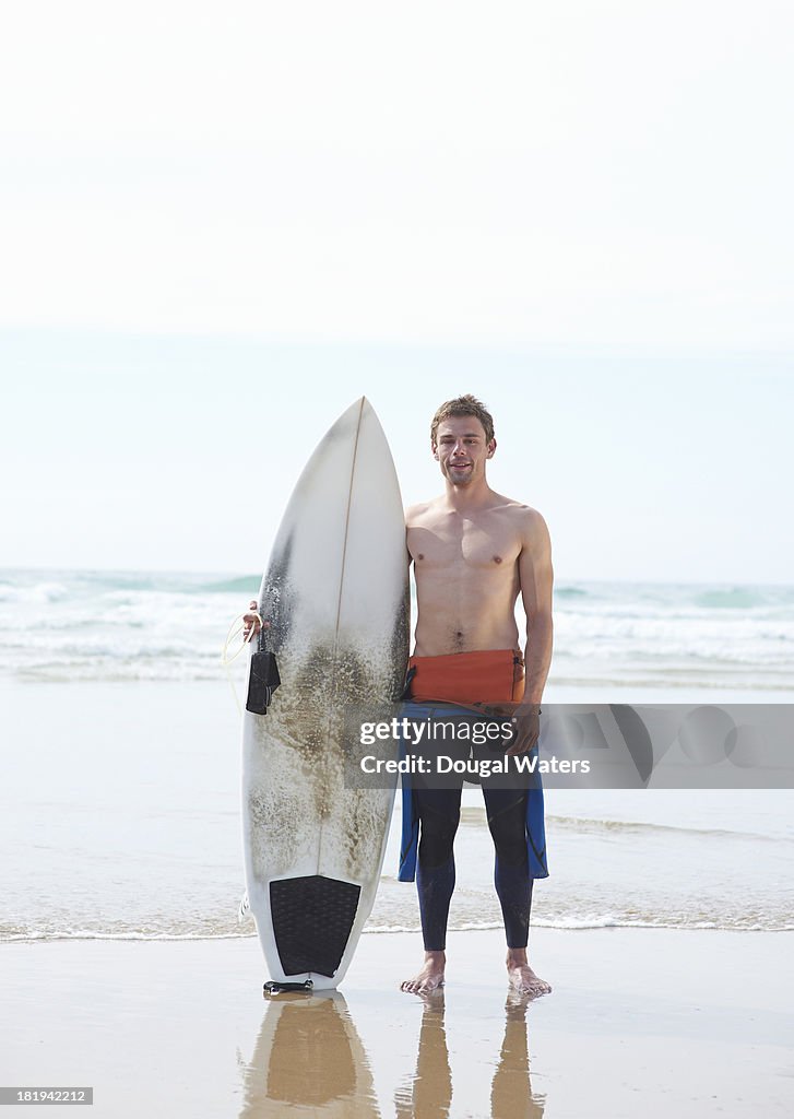 Surfer with surf board beside sea.