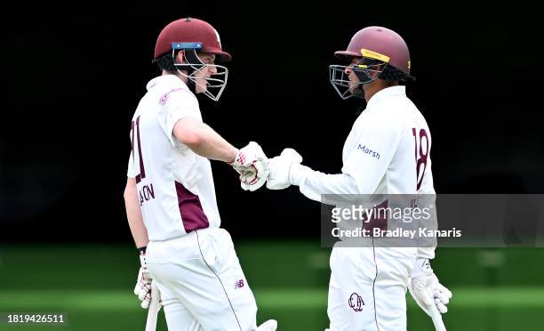 Jack Clayton and Usman Khawaja of Queensland pump fists as they talk tactics during day two of the Sheffield Shield match between Queensland and...