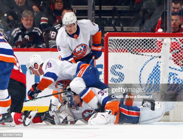 Brock Nelson falls over Ilya Sorokin of the New York Islanders knocking his mask off during the third period against the New Jersey Devils at...