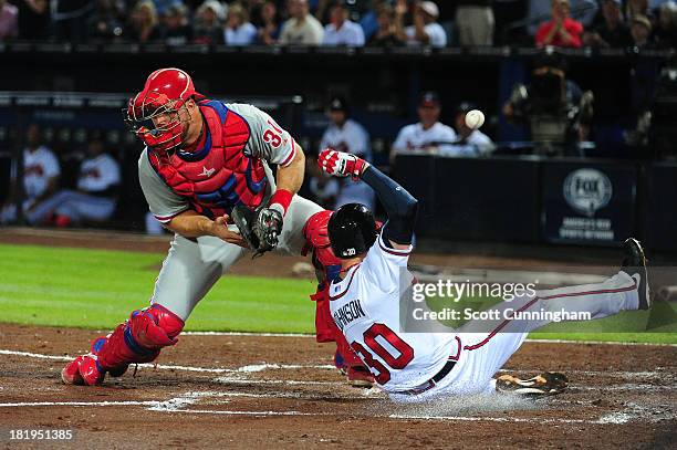 Elliot Johnson of the Atlanta Braves scores a second-inning run against Erik Kratz of the Philadelphia Phillies at Turner Field on September 26, 2013...