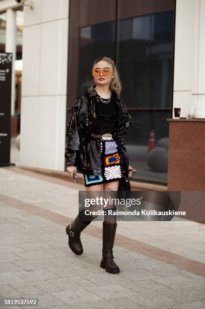Guest wears black top, black sequin jacket, long black socks, black boots and knitted colourful mini skirt during the Tashkent Fashion Week 2023 on...