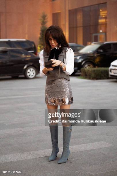 Guest wears Diesel blue shoes, silver metal imitation mini skirt, Celine bag, white shirt and grey vest during the Tashkent Fashion Week 2023 on...