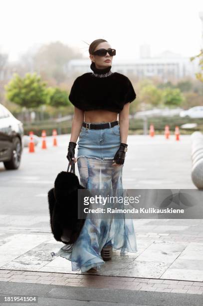 Guest wears long skirt part blue denim, part white and blue silk with a black belt, black leather gloves from Dolce & Gabbana, black big fur bag,...