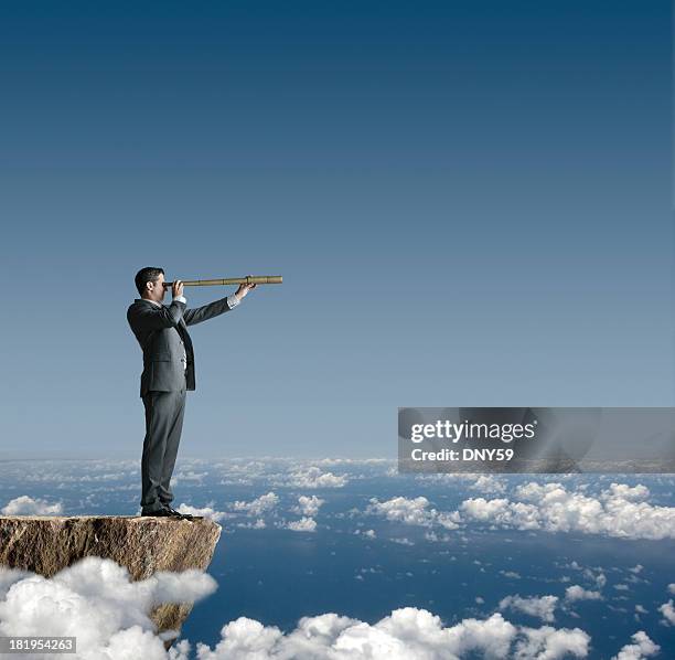 businessman standing on cliff looking through spyglass - handtelescoop stockfoto's en -beelden