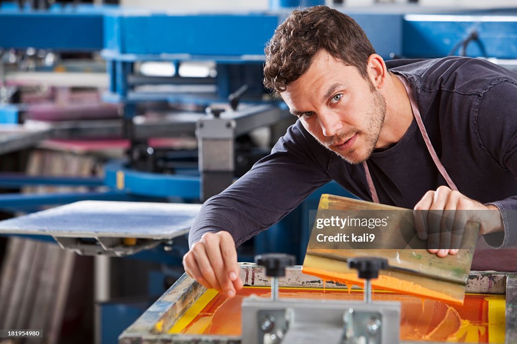 Man operating screen printing equipment