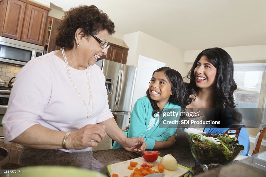 Three generations of women preparing dinner in family kitchen