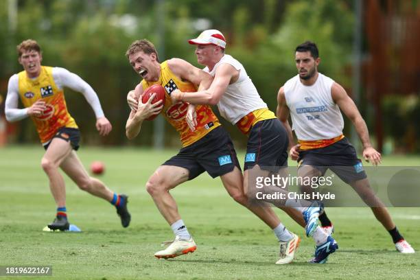 Noah Anderson is tackled by Bailey Humphrey during a Gold Coast Suns AFL training session at Heritage Bank Stadium on November 29, 2023 in Gold...